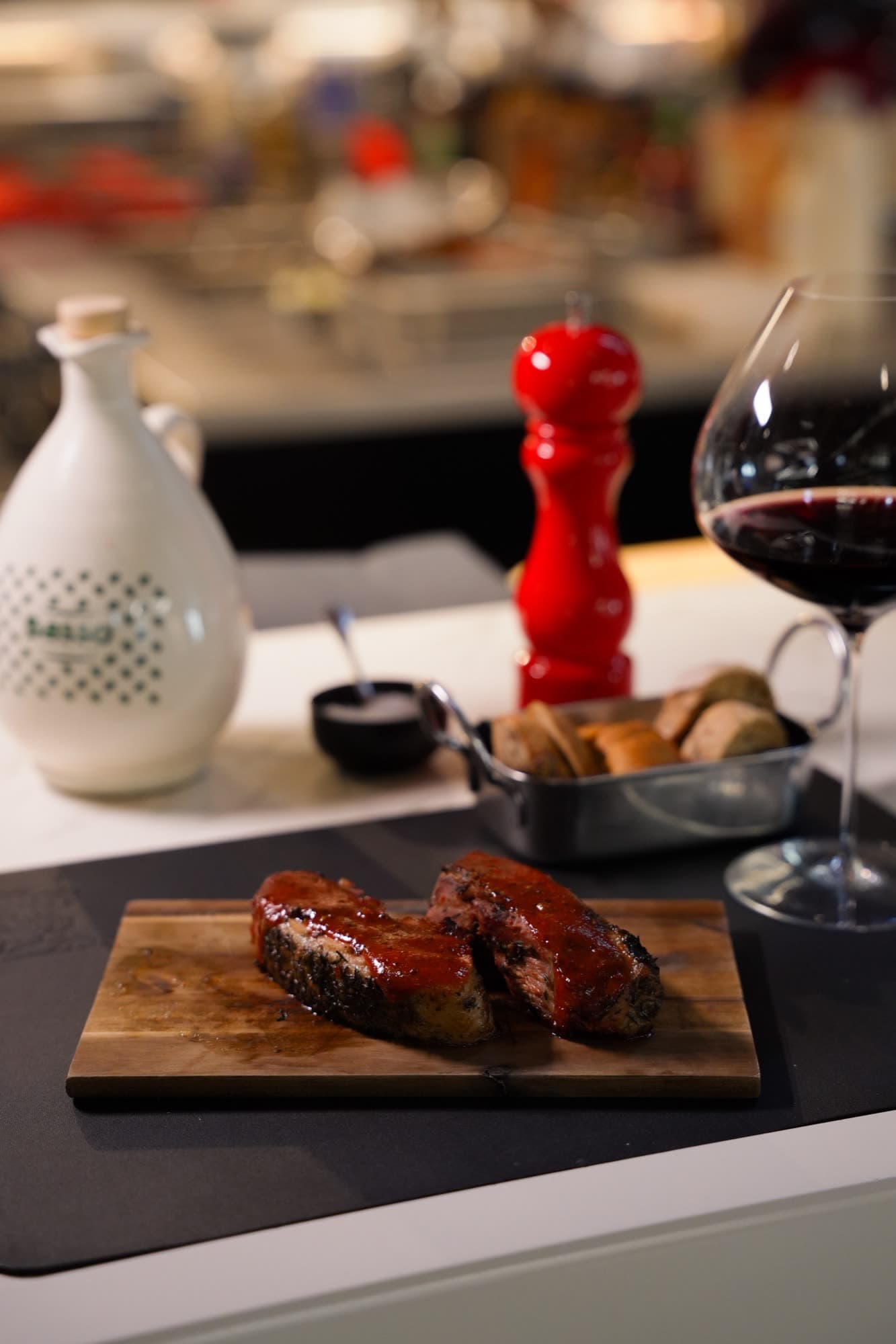 Steak on wooden board with wine glass and red pepper grinder