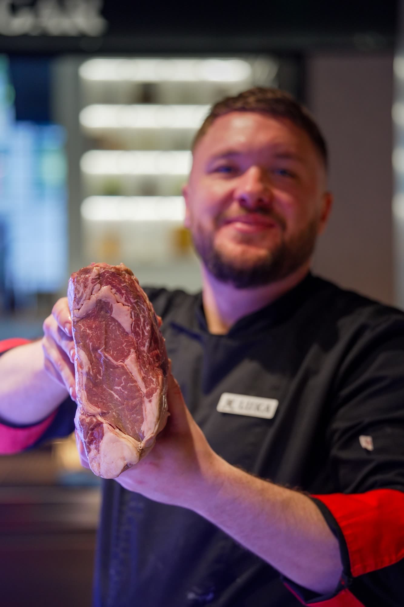 Chef Luka holding a T-bone steak, smiling