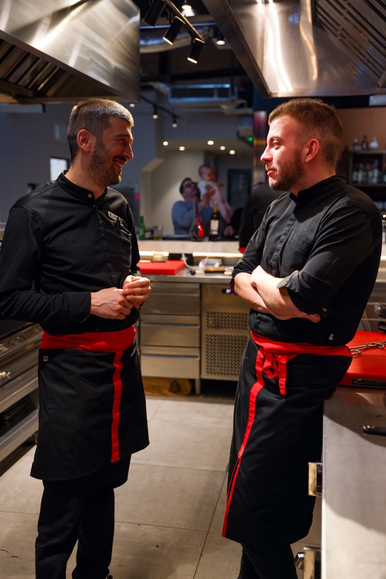 Two chefs in full uniform talking in the open kitchen