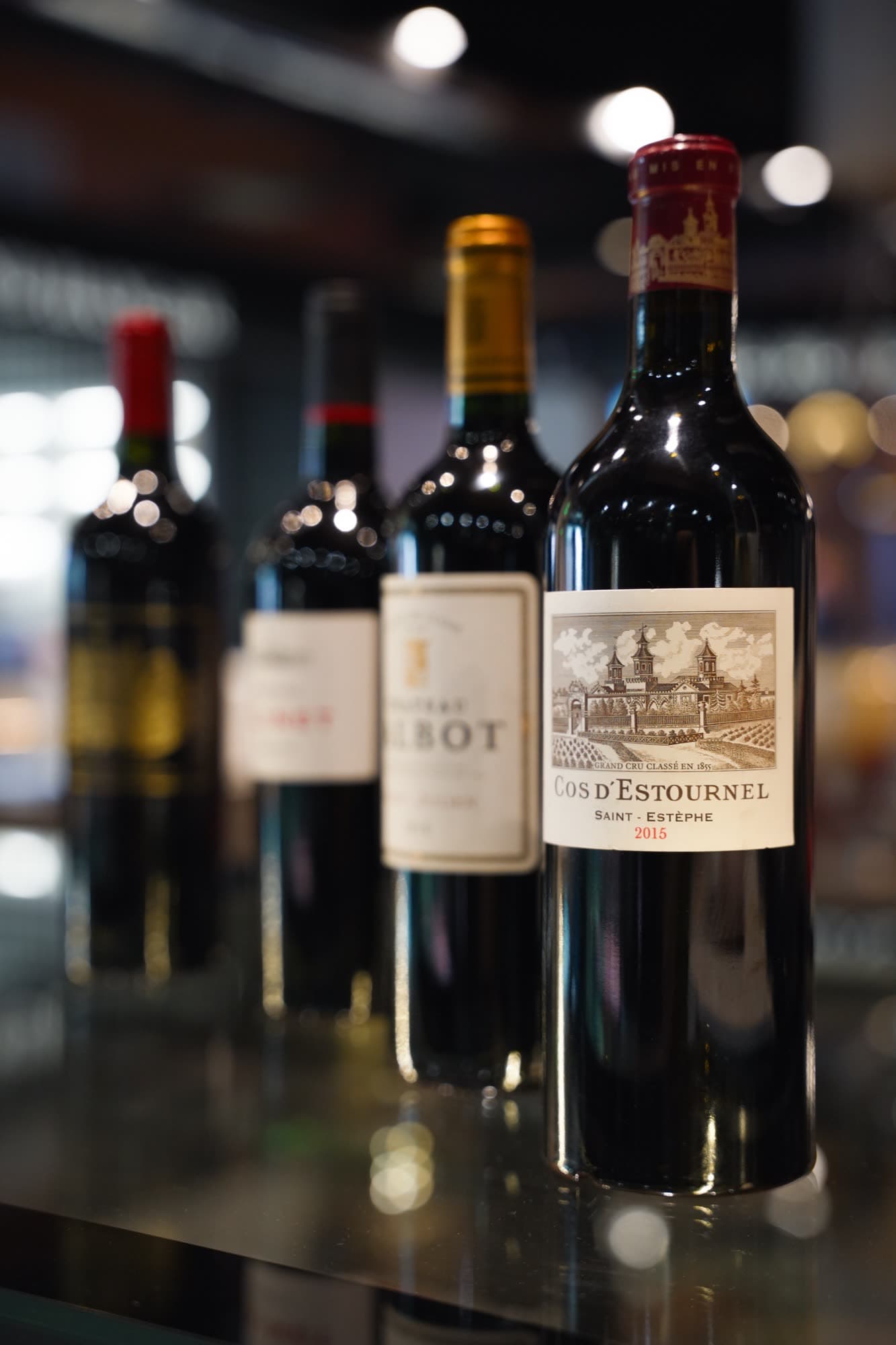 Wine bottles lined up on a shelf under warm lighting